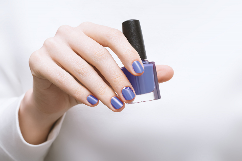 female-hand-with-purple-nail-design-holding-nail-polish-bottle