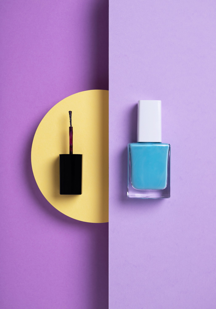 vertical-overhead-shot-blue-nail-polish-black-applicator-geometric-yellow-purple-background (1)